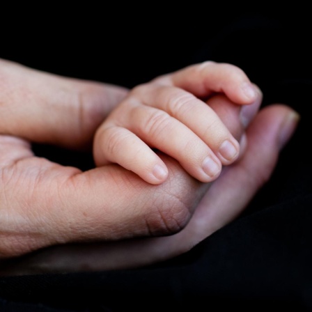 Eine grosse Hand hält eine Kinderhand.