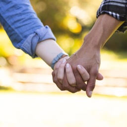 Blick auf die Hände eines Pärchens, das Hand in Hand spazieren geht. (Symbolbild)