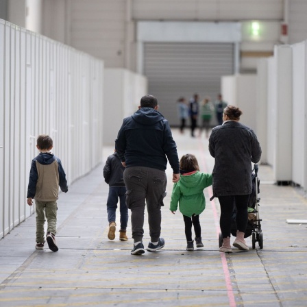 Eine Flüchtlingsfamilie geht durch die zu einer Massenunterkunft umfunktionierten Messehalle in Frankfurt.