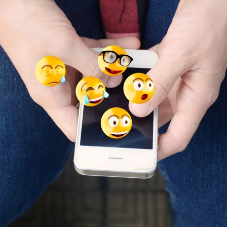 Mann versendet Emojis mit einem Smartphone