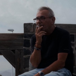 Ein Mann sitzt am Strand und zieht sinnierend an einer Zigarette