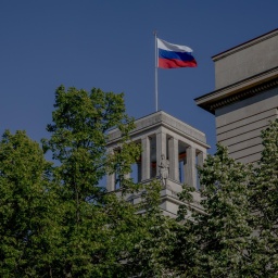 Die russische Fahne über der Botschaft der Russischen Föderation in Berlin und grüne Baumkronen. 