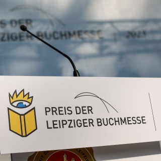 Ein Schild „Preis der Leipziger Buchmesse“ hängt vor der Preisverleihung an einem Rednerpult.