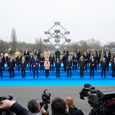 Staats- und Regierungschefs stehen für ein Gruppenfoto vor dem Atomium, einer Skulptur atomarer Verbindungen