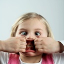 Ein Kind zieht ein lustiges Gesicht: Es schielt und zieht mit beiden Händen den Mund in eine große Fratze.