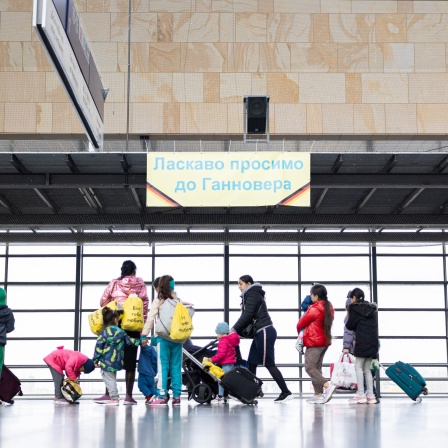 Geflüchtete aus der Ukraine laufen nach ihrer Ankunft durch die Eingangshalle vom Messebahnhof Laatzen