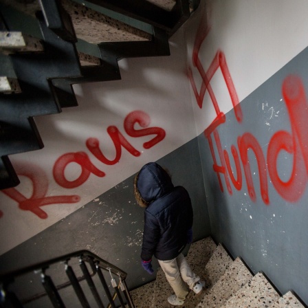 Ein Hakenkreuz und die Wörter Raus und Hunde sind am 13.10.2015 im Treppenhaus einer Asylbewerberunterkunft in Waltrop (Nordrhein-Westfalen) zu lesen.