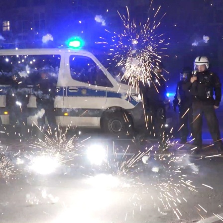 Polizeibeamte stehen hinter explodierendem Feuerwerk.