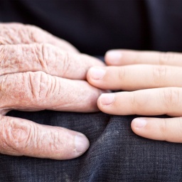 Kinderhand berührt Seniorenhand.