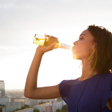 Eine Frau trinkt aus einer Flasche Bier.