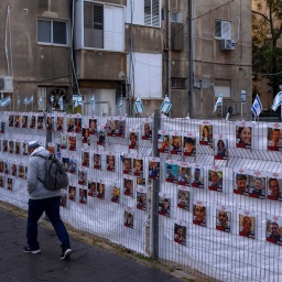 Israel, Ramat Gan: Ein Mann geht an einem Zaun mit Fotos von Geiseln vorbei