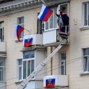 Arbeiter hängen russische Fahnen an einem Wohnhaus in der von Russland unterstützten und von Separatisten kontrollierten Volksrepublik Luhansk auf.