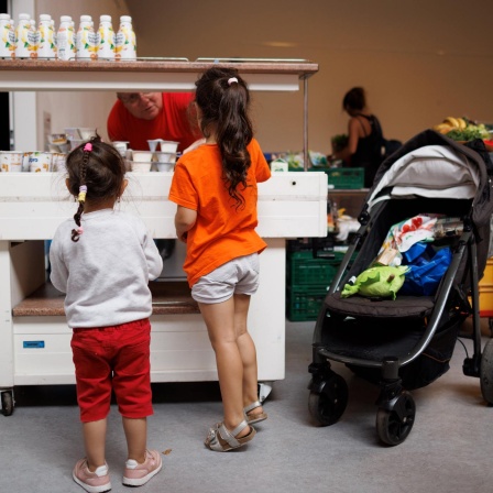 Ein Mitarbeiter verteilt Jogurt an zwei Kinder in der Ausgabestelle der Berliner Tafel. (Bild: dpa) 