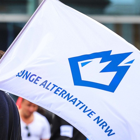 Eine Person trägt eine Fahne mit dem Logo der "Jungen Alternative NRW", der Jugendorganisation der AfD (2022).