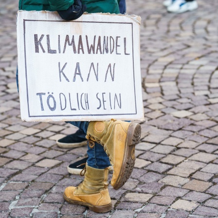 Eine Teilnehmerin des Globalen Fridays for Future Streiks stellt auf ihrem Fuss ein Schild &#034;Klimawandel kann Tödlich sein&#034; ab.