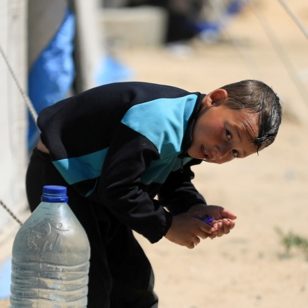 Ein Junge kühlt sich in Gaza mit Wasser ab