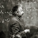 Albert Einstein um 1925. Der Physiker steht vor einer Tafel mit vielen Formeln