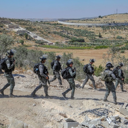 Israelische Soldaten gehen durch ein zerstörtes Gebiet.