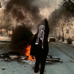Demonstrantin im Iran vor brennenden Gegenständen