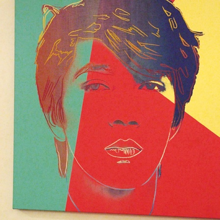Ryūichi Sakamoto steht neben dem Porträt, das Andy Warhol von ihm anfertigen ließ | Bild: picture alliance / Everett Collection | Salzgeber & Co. Medien GmbH