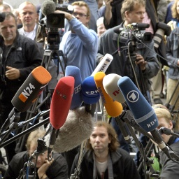 Kamerateams und Fotografen warten vor einer Pressekonferenz hinter Mikrofonen.