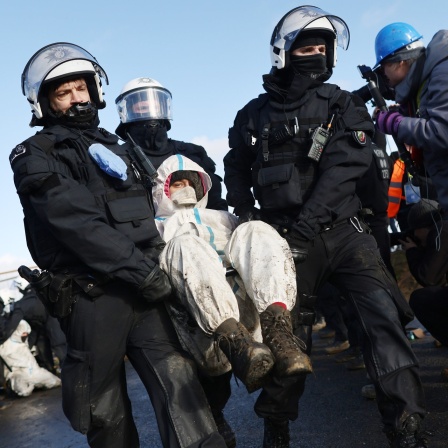 Polizisten tragen einen Klimaaktivisten vom besetzten Braunkohleort Lützerath weg.