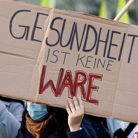 Das Beitragsbild des Dok5 Feature "Gesundheit neu Denken" zeigt ein Plakat auf einer Demonstration mit der Aufschrift "Gesundheit ist keine Ware".