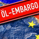 Schild mit der Aufschrift Öl-Embargo vor den Fahnen von EU und Russland