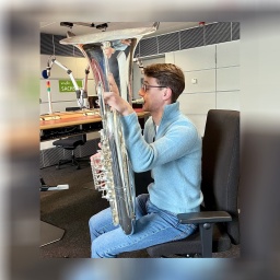 Ein Mann sitzt auf einem Stuhl und hält eine Tuba