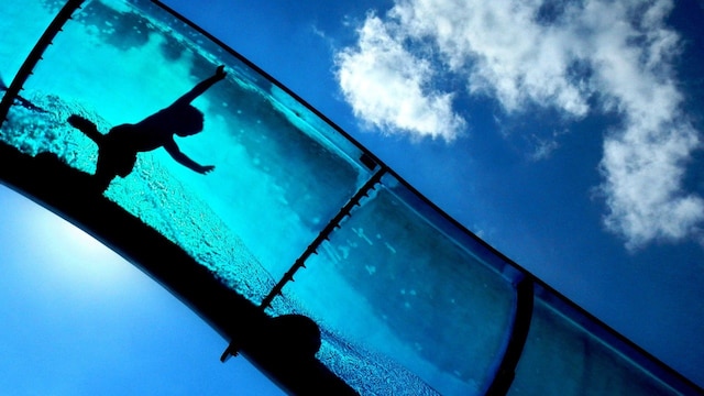 Die Silhouette eines Kindes zeichnet sich in einer Wasserrutsche in einem Freibad ab