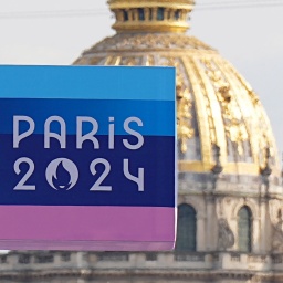 Eine Anzeigetafel mit dem Logo der Spiele und die Olympischen Ringe sind vor der Kuppel des Invalidendoms zu sehen.