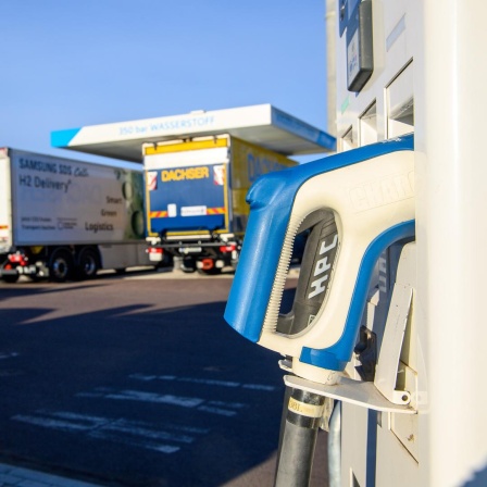 Eine Ladestation für Elektrofahrzeuge. Im Hintergrund stehen Lastwagen an einer Wasserstofftankstelle. 