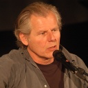 Georg Danzer vor einem Mikrofon vor dunklem Hintergrund