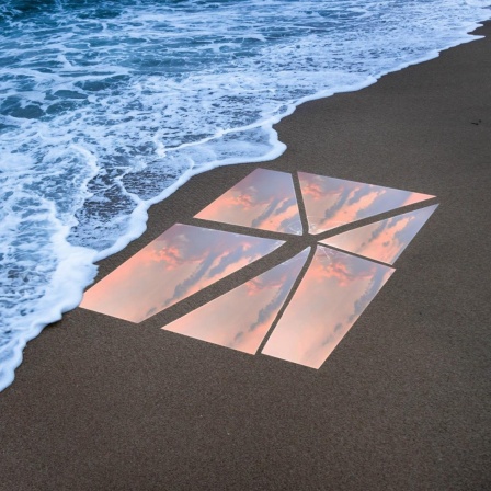 Ein zebrochener Spiegel liegt am Strand und spiegelt den Sonnenuntergang.