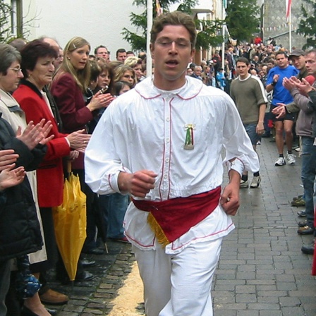 Der Raffer Jochen Floss läuft mit einem rohen Ei in der Faust durch den Eifelort Schönecken.