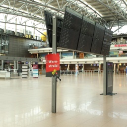 Menschenleeres Terminal 1 im Flughafen Hamburg. An der Anzeige für Ankünfte und Abflüge ist ein Plakat mit der Aufschrift "Warnstreik" angebracht.