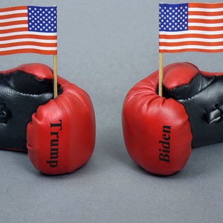 Zwei Boxhandschuhe mit Aufschrift "Trump" und "Biden", die kleine US-Flaggen halten