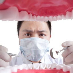 Zahnarzt schaut in Mund