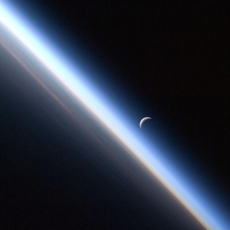Blick auf die Erdatmosphäre (mit der Mondsichel im Hintergrund), aufgenommen von Bord der ISS. 