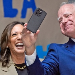 Kamala Harris (links, verdeckt) und Tim Walz lachen bei einer Wahlkampfveranstaltung