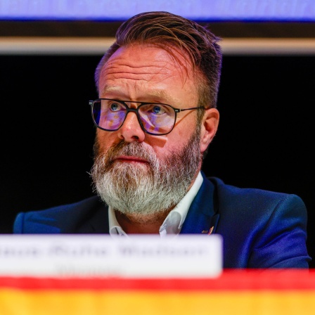 Schleswig-Holsteins Verkehrsminister Claus Ruhe Madsen (CDU) sitzt auf einem Podium. 