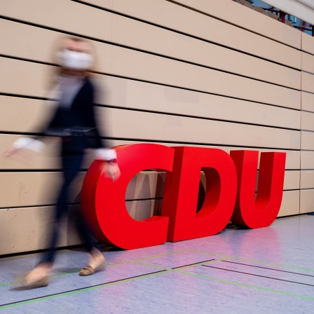 Eine Frau läuft an einem CDU Logo vorbei.