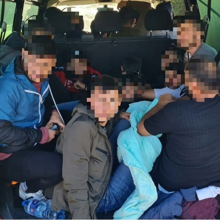 Zahlreiche Menschen liegen im Kofferraum eines Kleinbuses