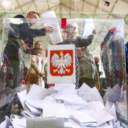 Polnische Bürger stecken ihre Wahlzettel anlässlich der Parlamentswahlen in eine gläserne Wahlurne