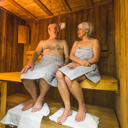 Ein Mann und eine Frau sitzen in einer Sauna.