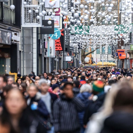 Menschen gehen in Köln durch die Einkaufsmeile Hohe Straße in der Fußgängerzone. 