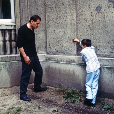 Ein Mann und ein Junge stehen sich gegenüber und lehnen an einer Wand. Eine Szene aus dem Film "Der Boxer".