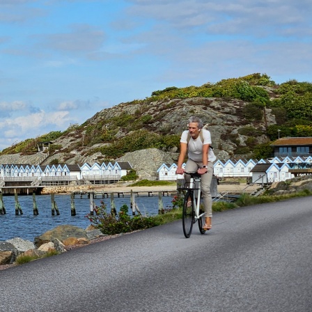 Ein Mann fährt Fahrrad am Rande des Meeres in Schweden