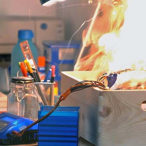 Flammen schlagen aus einer Holzkiste mit Kabeln