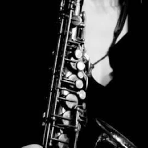 JUnge Frau mit einem Saxophon vor sich / schwarz-weiß Bild